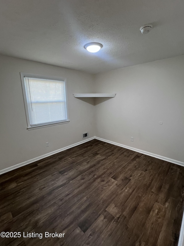 empty room with a textured ceiling and dark hardwood / wood-style floors