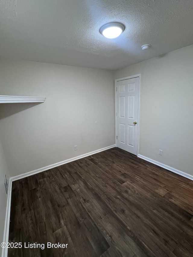 unfurnished room with dark hardwood / wood-style flooring and a textured ceiling