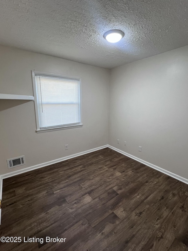 unfurnished room featuring dark hardwood / wood-style flooring and a textured ceiling