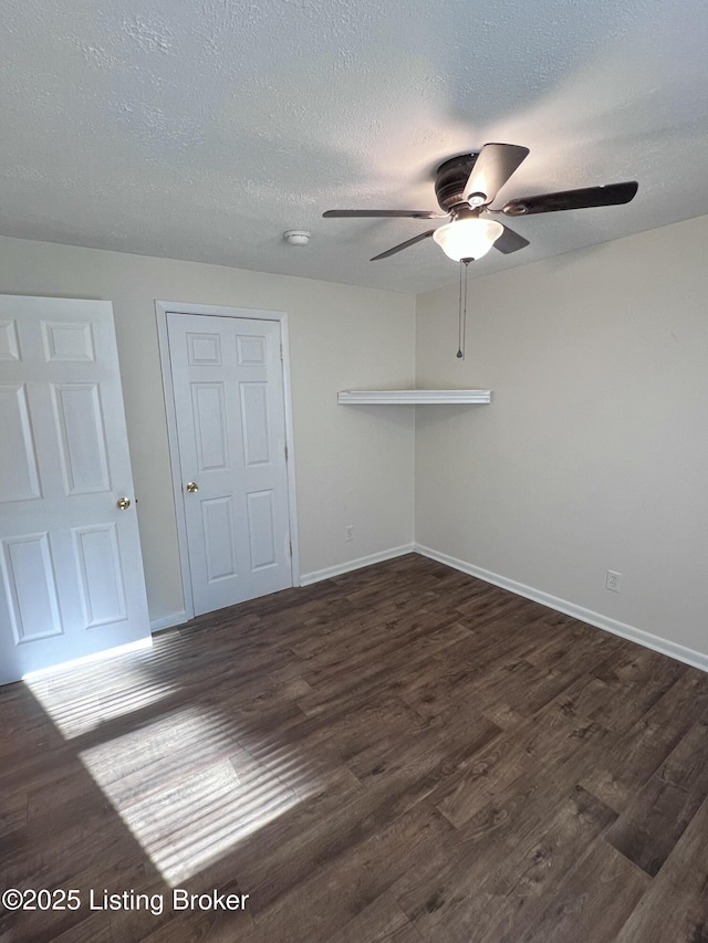 empty room with ceiling fan, dark hardwood / wood-style flooring, and a textured ceiling