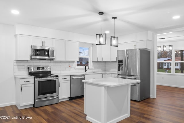 kitchen featuring a kitchen island, sink, hanging light fixtures, stainless steel appliances, and white cabinets