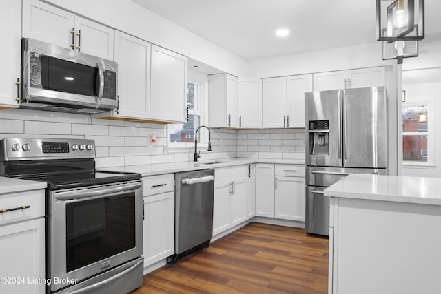 kitchen featuring appliances with stainless steel finishes, backsplash, dark wood-type flooring, white cabinets, and sink