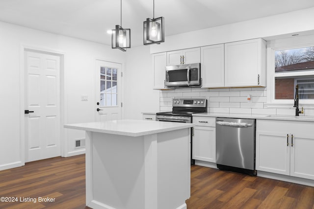 kitchen with appliances with stainless steel finishes, a center island, white cabinetry, sink, and hanging light fixtures