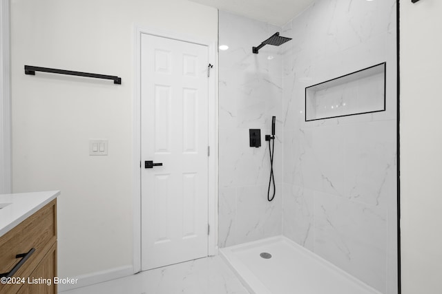 bathroom featuring a tile shower and vanity