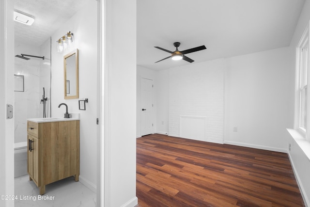 bathroom featuring ceiling fan, vanity, hardwood / wood-style flooring, a shower, and a textured ceiling