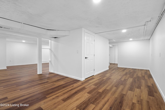 basement with a textured ceiling and dark hardwood / wood-style floors