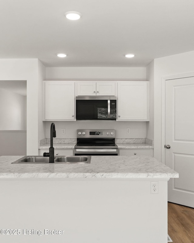 kitchen with recessed lighting, stainless steel appliances, wood finished floors, a sink, and white cabinets