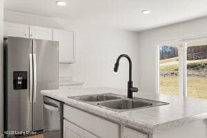 kitchen featuring white cabinetry, stainless steel appliances, a sink, and light countertops