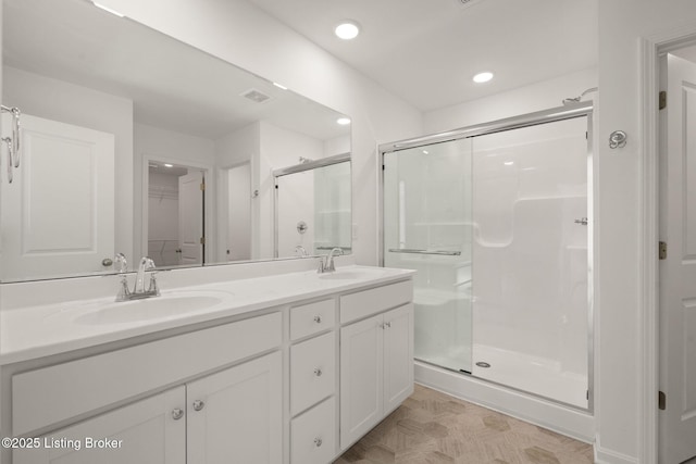 full bathroom with a sink, double vanity, a spacious closet, and a shower stall