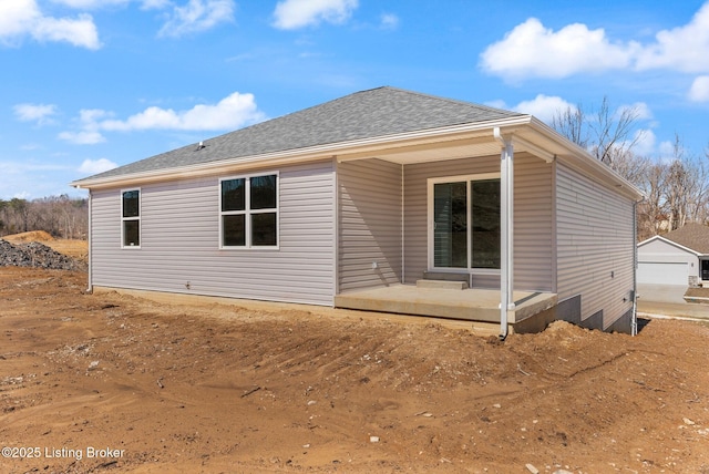 rear view of property featuring a shingled roof and a patio