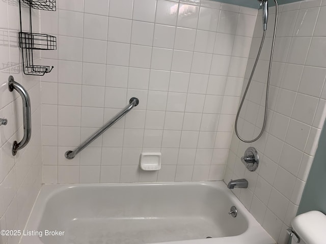 bathroom featuring toilet and tiled shower / bath