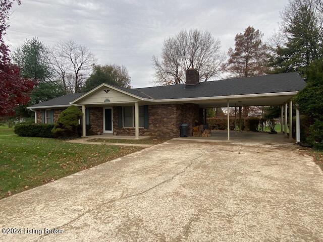 view of front facade with covered porch, a front yard, and a carport