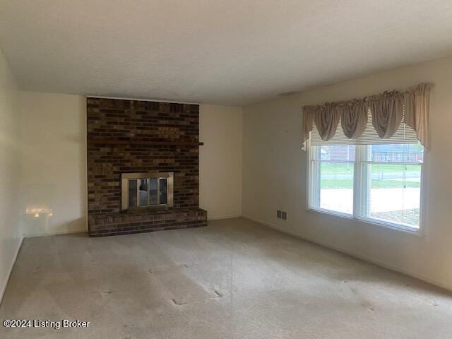 unfurnished living room with light colored carpet and a brick fireplace