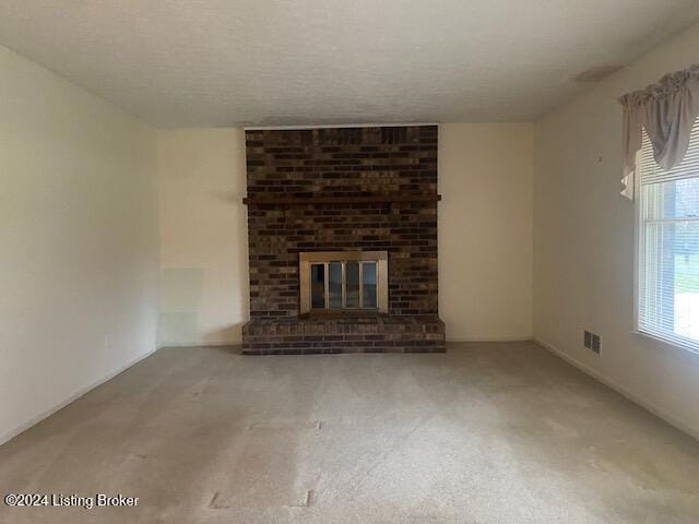 unfurnished living room featuring carpet, a fireplace, and a textured ceiling