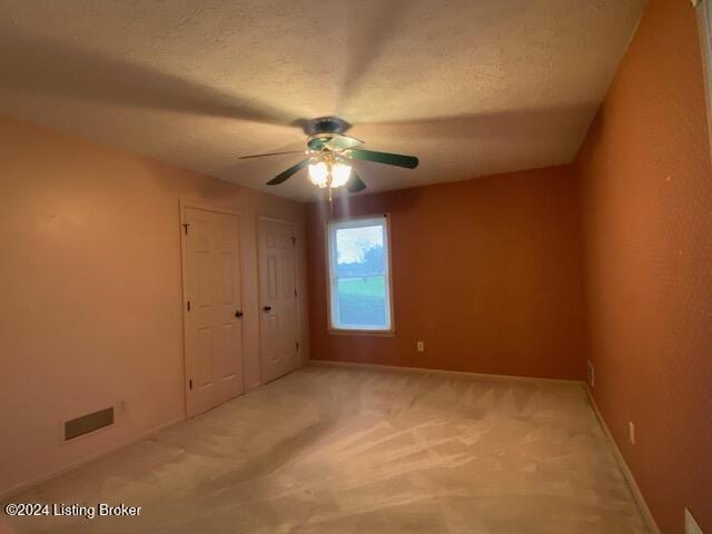 empty room featuring ceiling fan, a textured ceiling, and carpet flooring