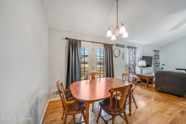 dining space with a chandelier, light hardwood / wood-style flooring, and lofted ceiling