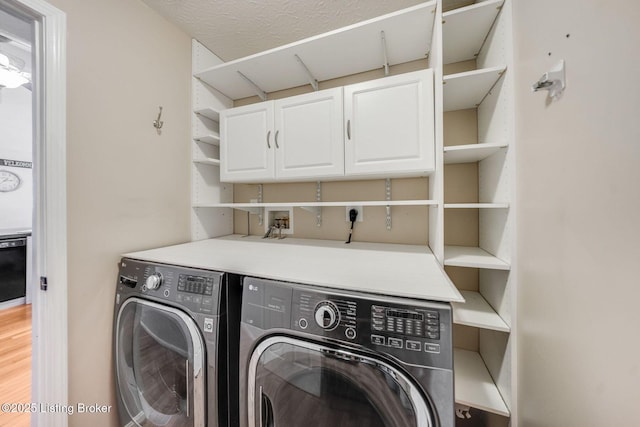 washroom featuring separate washer and dryer, a textured ceiling, cabinets, and wood-type flooring