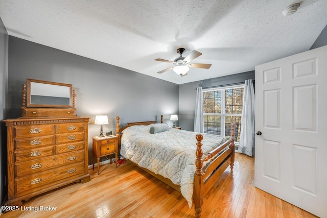 bedroom with a textured ceiling, light hardwood / wood-style flooring, and ceiling fan