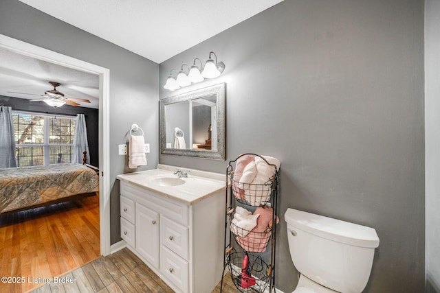 bathroom featuring wood-type flooring, toilet, ceiling fan, and vanity