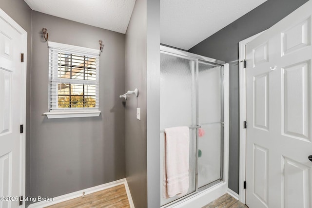 bathroom featuring a shower with shower door, hardwood / wood-style floors, and a textured ceiling