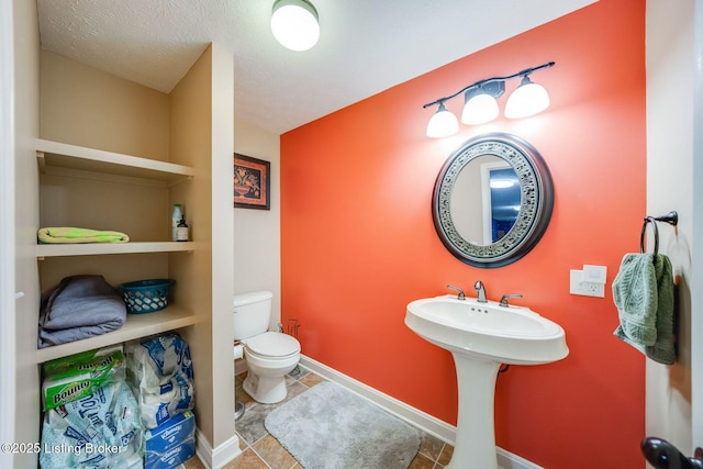 bathroom featuring a textured ceiling, built in features, toilet, and tile patterned floors