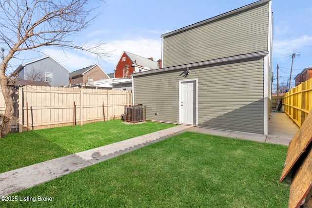 rear view of house featuring central AC and a lawn