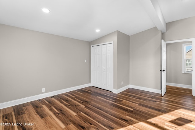 unfurnished bedroom with vaulted ceiling with beams, a closet, and dark hardwood / wood-style floors