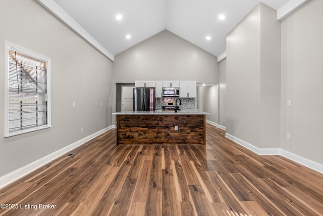 interior space with dark wood-type flooring, white cabinetry, tasteful backsplash, sink, and black fridge