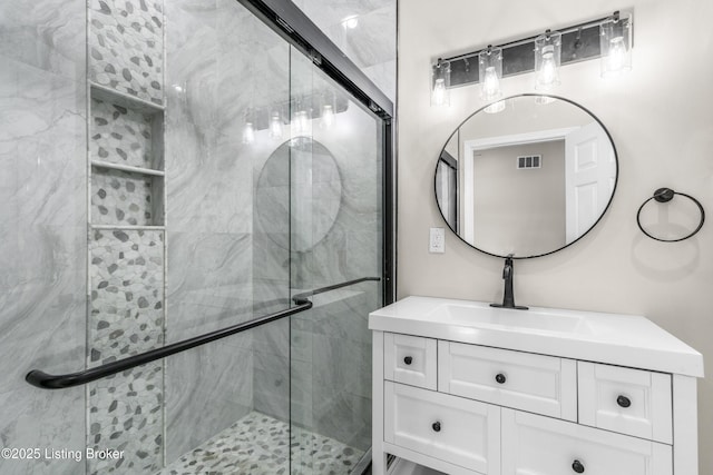 bathroom featuring a shower with shower door and vanity