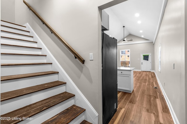 stairway featuring ceiling fan, lofted ceiling, and hardwood / wood-style floors