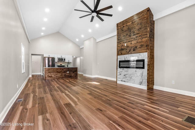 unfurnished living room featuring a premium fireplace, ceiling fan, hardwood / wood-style floors, and high vaulted ceiling