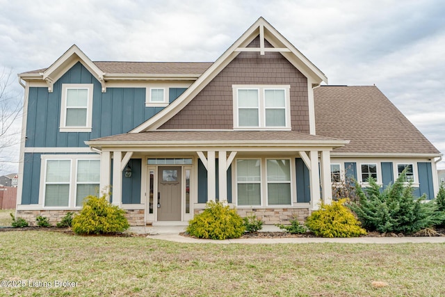 craftsman-style house featuring stone siding, roof with shingles, board and batten siding, and a front lawn