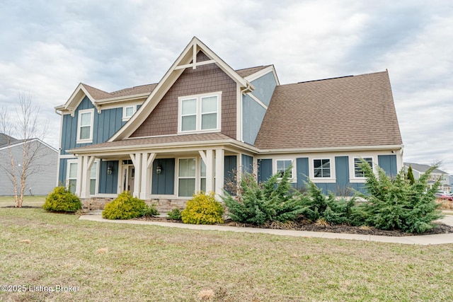 craftsman house with a porch, stone siding, board and batten siding, and a front yard