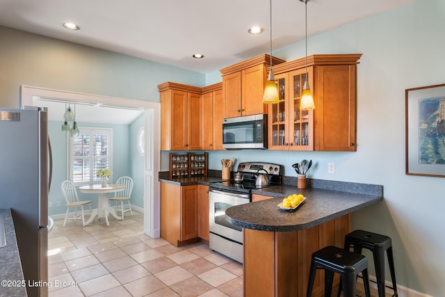 kitchen featuring pendant lighting, light tile patterned floors, appliances with stainless steel finishes, a kitchen breakfast bar, and kitchen peninsula