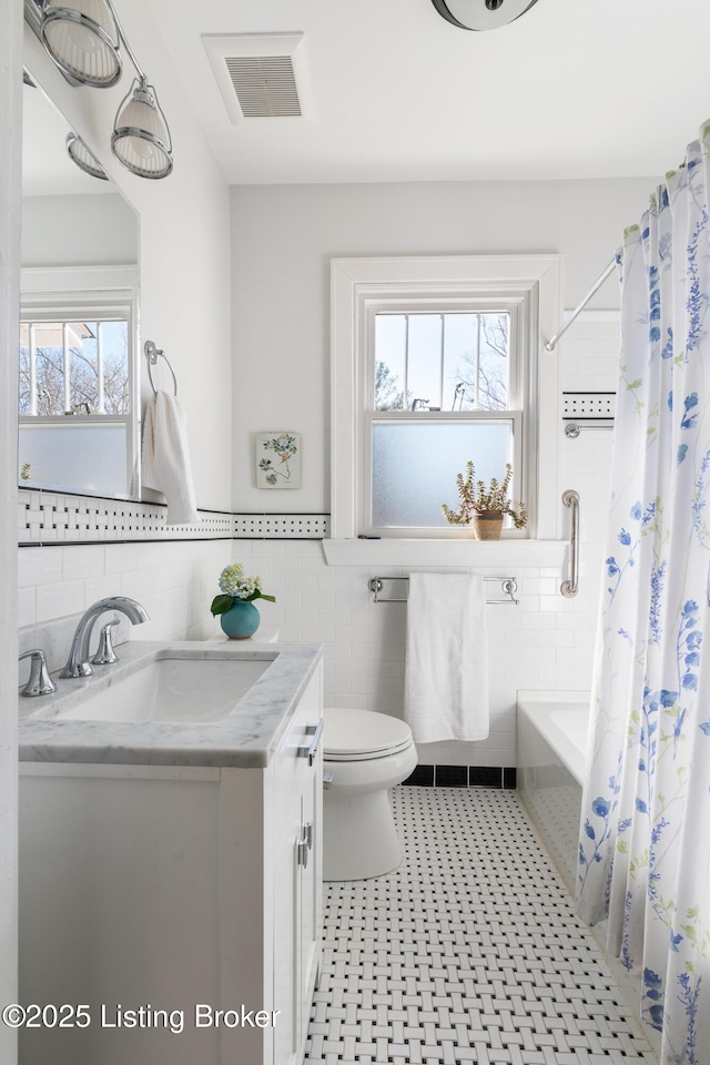 full bathroom with tile walls, vanity, shower / bath combination with curtain, tile patterned floors, and toilet