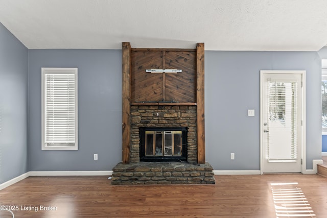 unfurnished living room featuring hardwood / wood-style floors and a stone fireplace