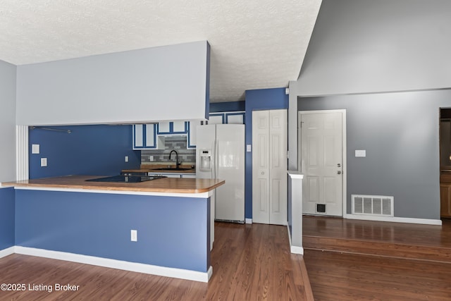 kitchen featuring sink, white refrigerator with ice dispenser, kitchen peninsula, and blue cabinets