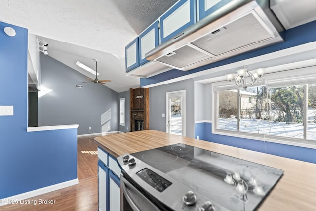 kitchen with lofted ceiling, a brick fireplace, extractor fan, stainless steel electric range, and blue cabinets