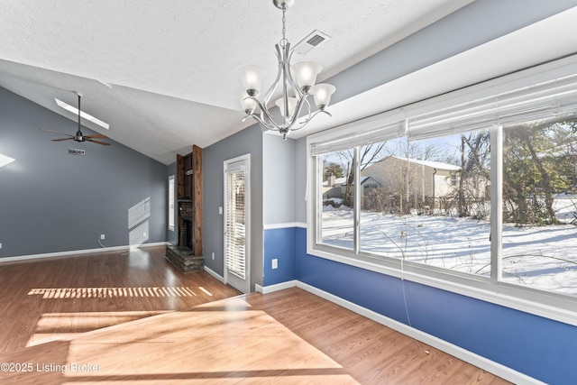 interior space featuring ceiling fan with notable chandelier, a textured ceiling, lofted ceiling, dark hardwood / wood-style floors, and a brick fireplace