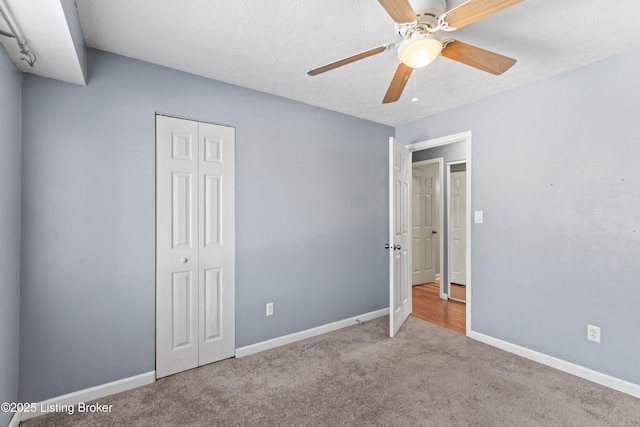 unfurnished bedroom featuring ceiling fan, light colored carpet, and a closet