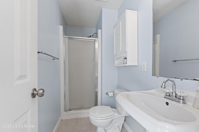 bathroom featuring a shower with shower door, sink, a textured ceiling, and tile patterned flooring