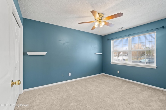 unfurnished room featuring ceiling fan, light colored carpet, and a textured ceiling