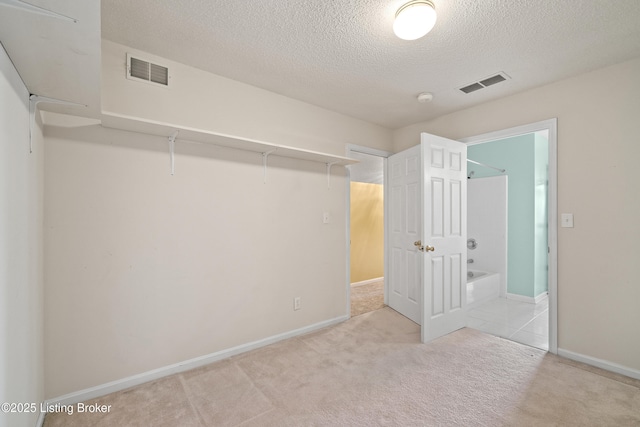 unfurnished bedroom featuring light carpet, a closet, and a textured ceiling