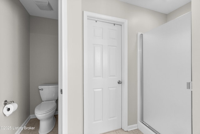 bathroom with a shower with door, tile patterned floors, and toilet