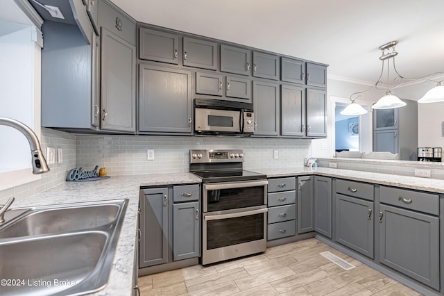 kitchen with tasteful backsplash, gray cabinets, pendant lighting, sink, and stainless steel appliances