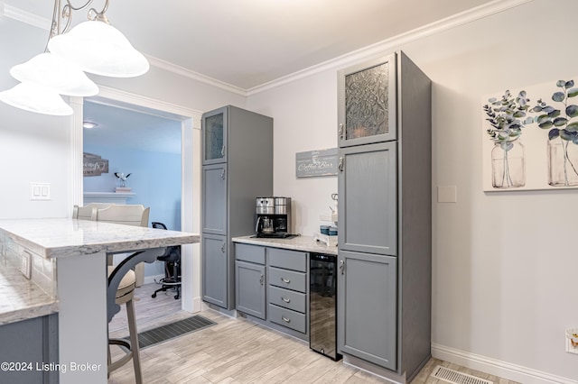 kitchen with gray cabinets, light hardwood / wood-style floors, a breakfast bar, hanging light fixtures, and beverage cooler