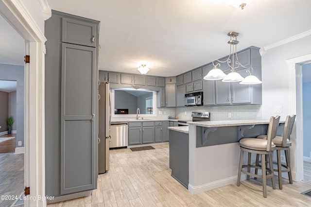 kitchen featuring stainless steel appliances, pendant lighting, a kitchen bar, and gray cabinets