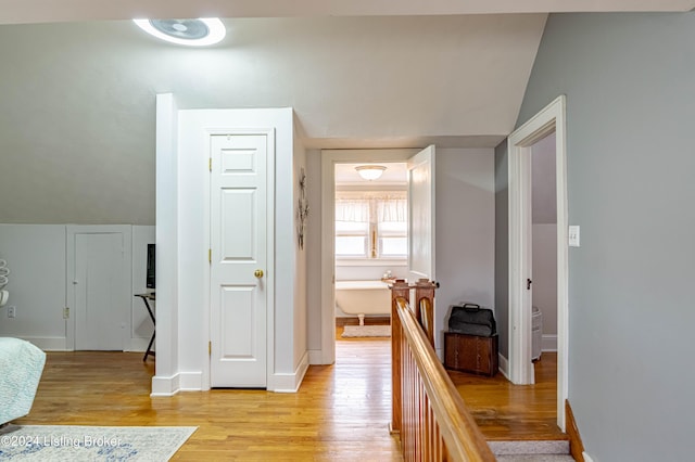 hall with light hardwood / wood-style floors and vaulted ceiling