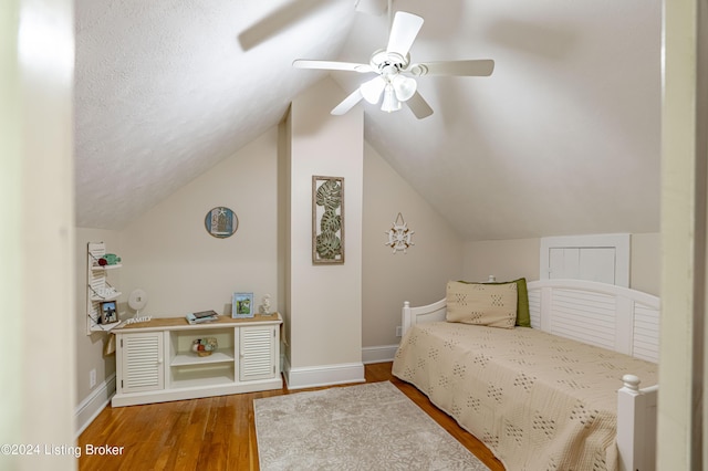 bedroom featuring ceiling fan, lofted ceiling, a textured ceiling, and hardwood / wood-style floors