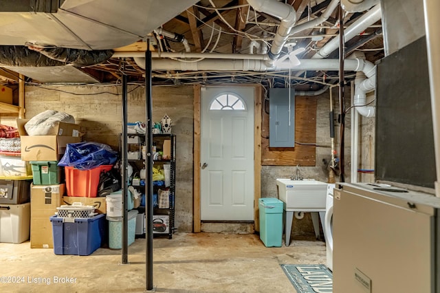 basement featuring sink, electric panel, and fridge